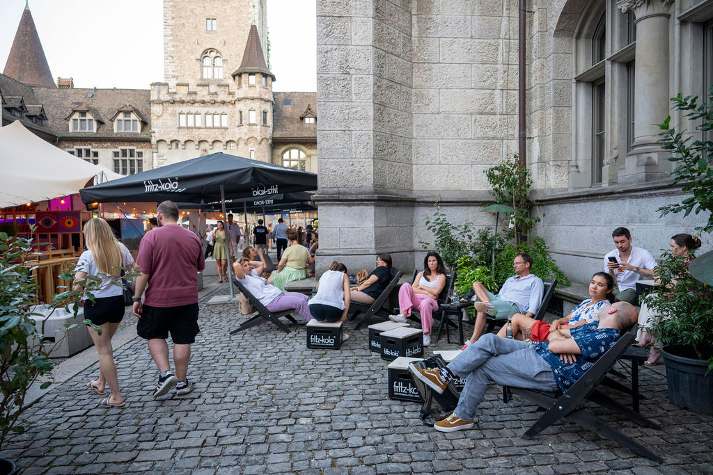 Gäste entspannen in Liegestühlen im Innenhof des Landesmuseums Zürich – entspannte Afterwork-Stimmung beim Hofkino