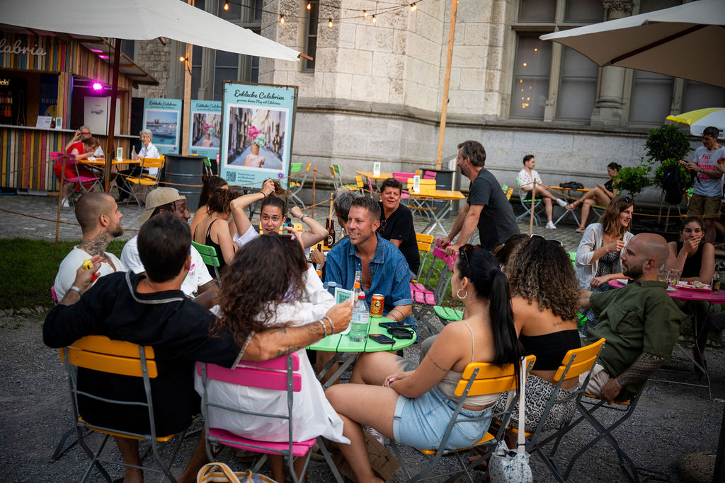 Freundesgruppe beim Abend im Freien beim Hofkino Zürich – lebhafte Stimmung mit Drinks an bunten Tischen im Innenhof des Landesmuseums